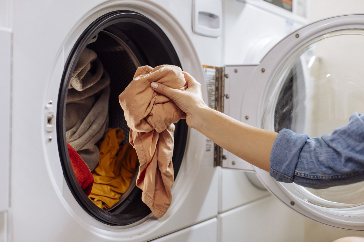 Person loading clothes into a front-loading washing machine